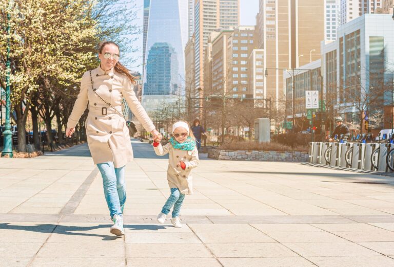 Young mother and little daughter walking near old houses in historic district of West Village